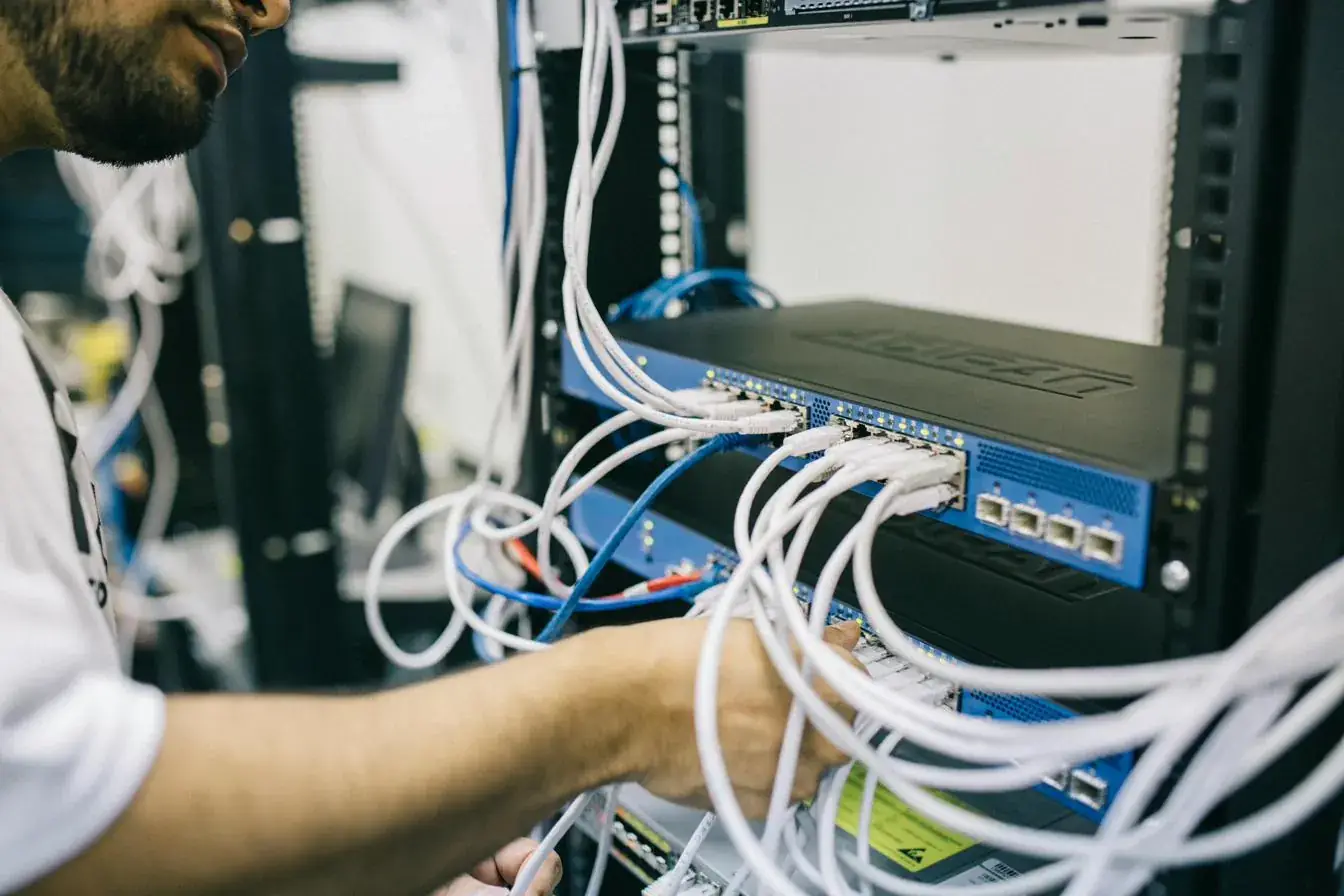 Technicien raccordant des câbles réseau sur un switch installé en baie